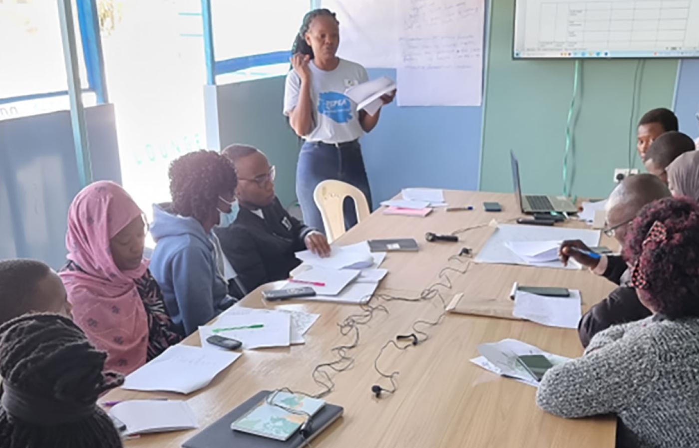 people around a table listening to a teacher