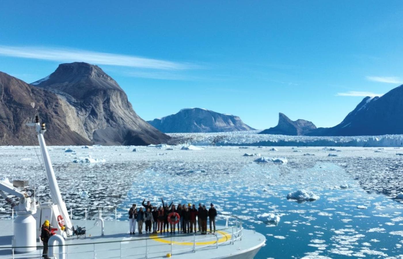 ship with people on deck in a fjord