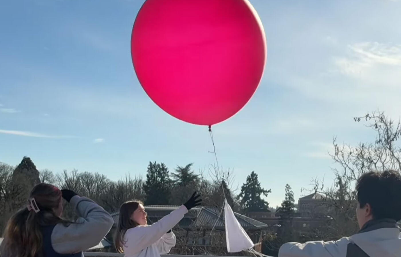 students launching a weather balloon from a building roof