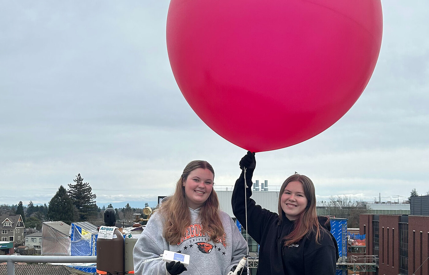 two students on a roof launching a weather balloon