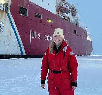 Genevieve on the ice in front of a Coast Guard ship