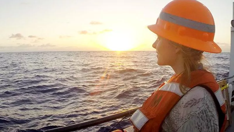 student on a ship looking at the sunset