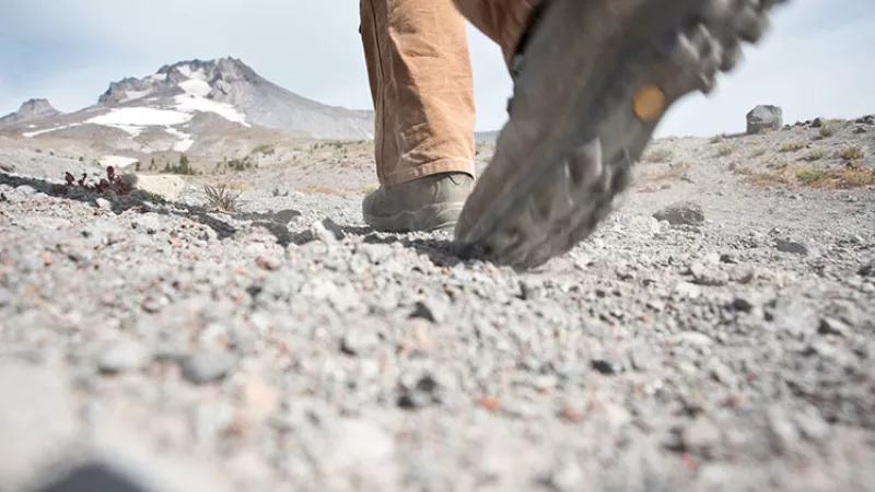 person wearing hiking boots walking on rocky ground