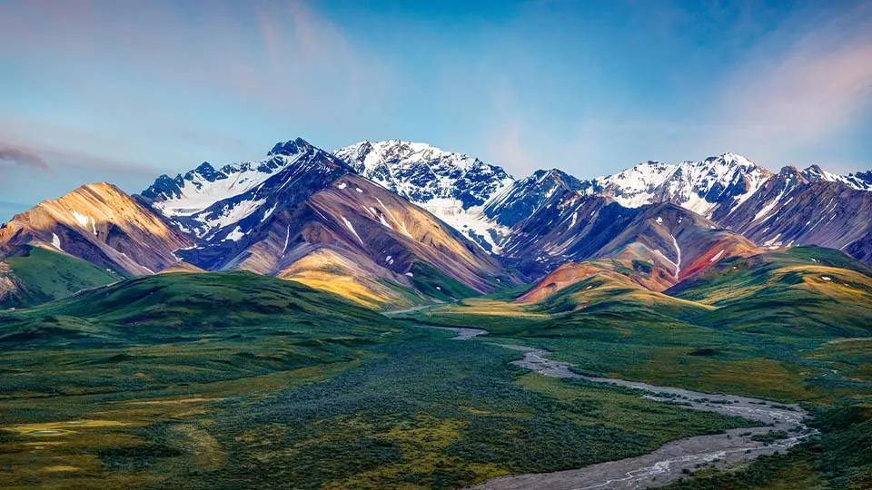 mountains behind a river running through a green landscape
