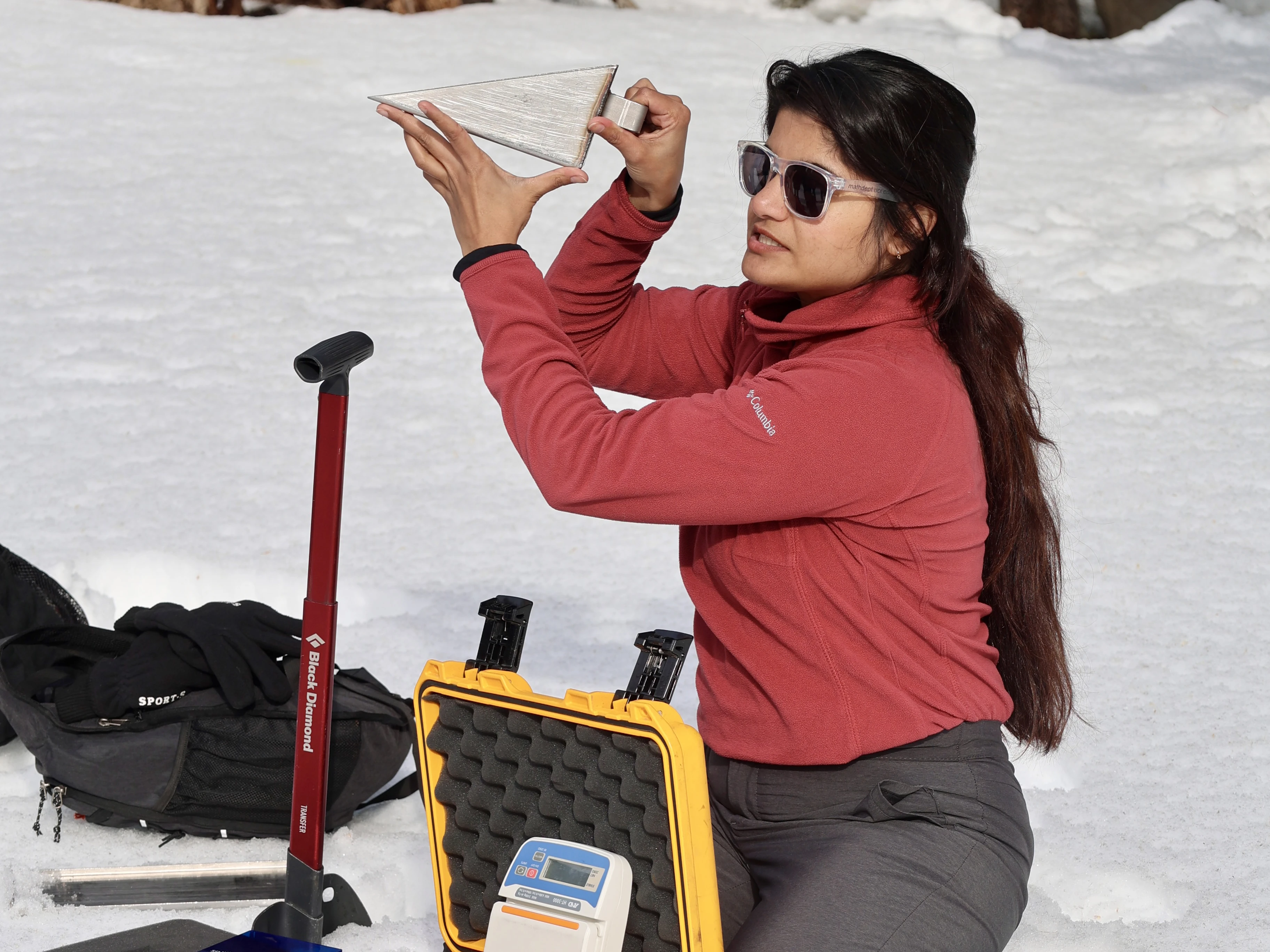 Woman in snow holding measuring device