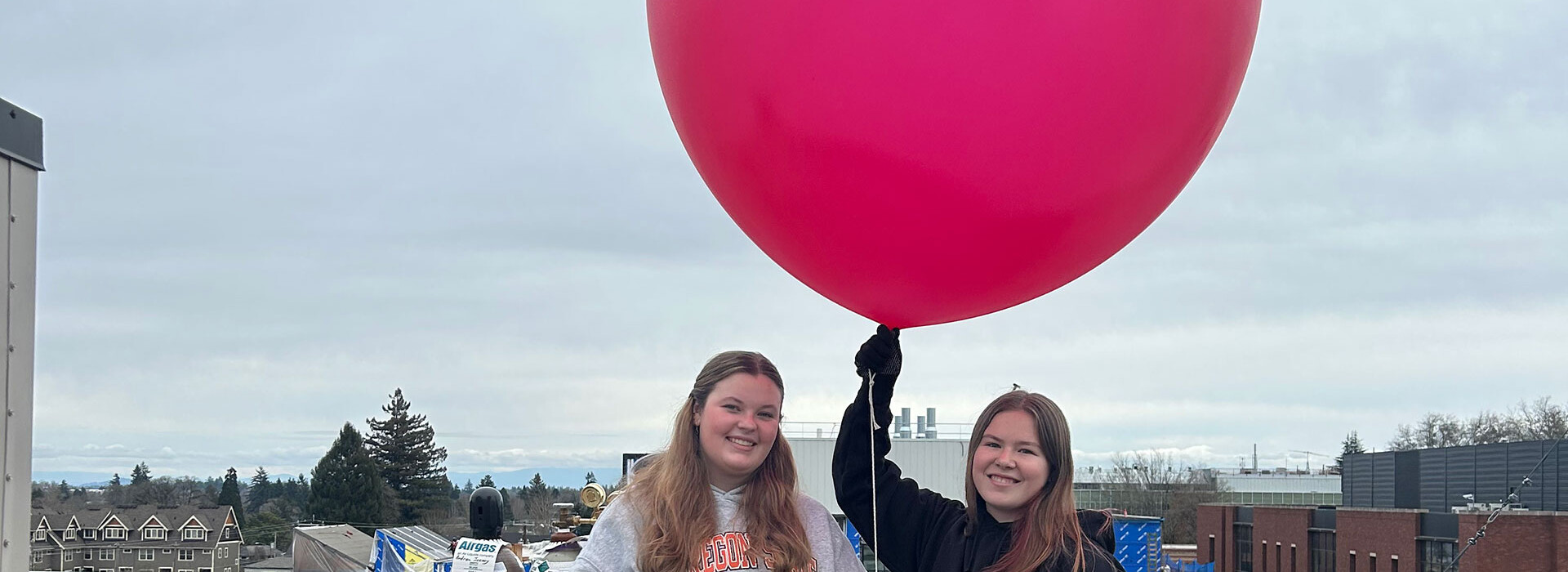 two students on a roof launching a weather balloon