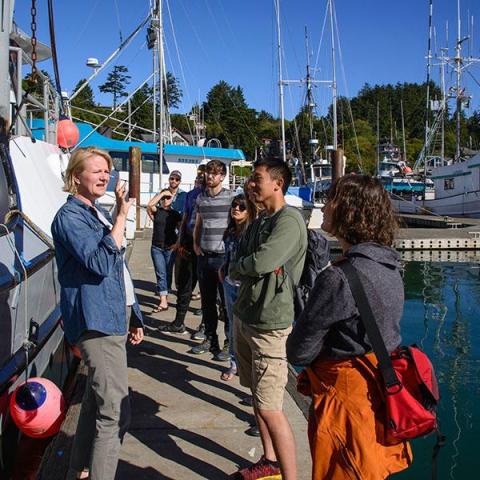 teacher and students on a dock in a harbor with boats