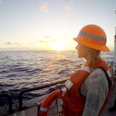 student on a ship looking at the sunset