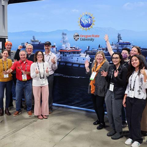 faculty in front of a large poster of a ship