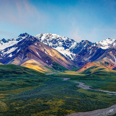 mountains behind a river running through a green landscape