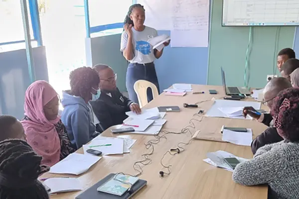 people around a table listening to a teacher