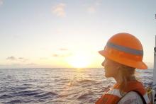 student on a ship looking at the sunset